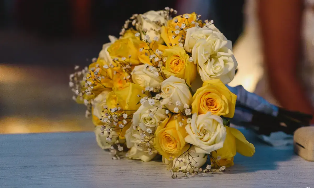 Un ramo de boda con rosas amarillas y blancas, adornado con pequeñas flores blancas.