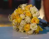 Un ramo de boda con rosas amarillas y blancas, adornado con pequeñas flores blancas.