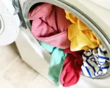 Carga de lavadora con ropa de colores variados, incluyendo rosa, amarillo, turquesa y rayas azules. ¡A ver si se puede lavar ropa blanca con ropa de color sin problemas!