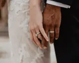 Manos entrelazadas, mostrando el anillo de casada en la mano izquierda de ella y el de él en la derecha.