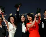 Ganadores celebran sus premios Goya 2026. Cinco personas sonríen alzando estatuillas doradas sobre un fondo oscuro con logos de patrocinadores.