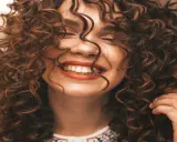 Mujer sonriendo con unos cortes de pelo rizado espectaculares, su cabello castaño cae en cascada alrededor de su rostro.