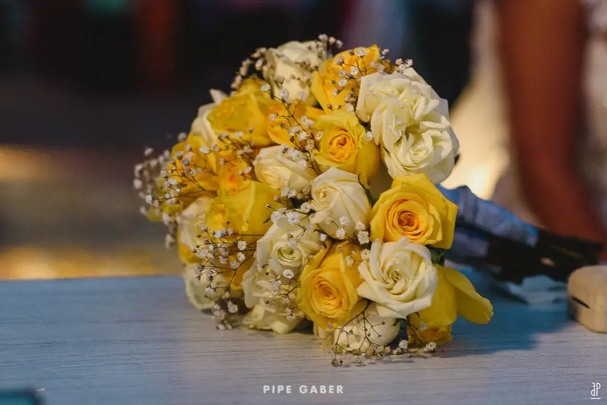 Un ramo de boda con rosas amarillas y blancas, adornado con pequeñas flores blancas.