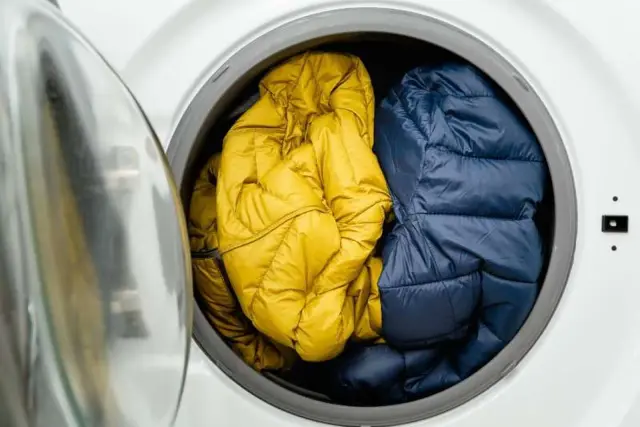 Dos chaquetas, una amarilla y otra azul, listas para lavar en la lavadora. Aprende como lavar un plumas en la lavadora para que queden como nuevos.