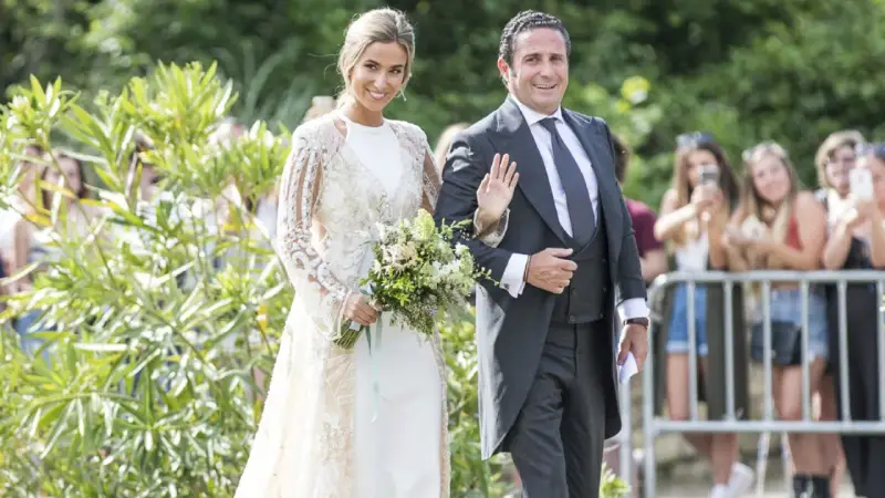 Novia y novio sonríen en la boda de María Pombo. Ella lleva un vestido blanco con encaje y él un traje gris.